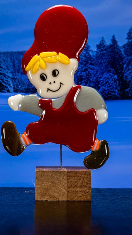 Glasfigur Nissedreng med lys grå bluse, løber mod venstre, på træfod