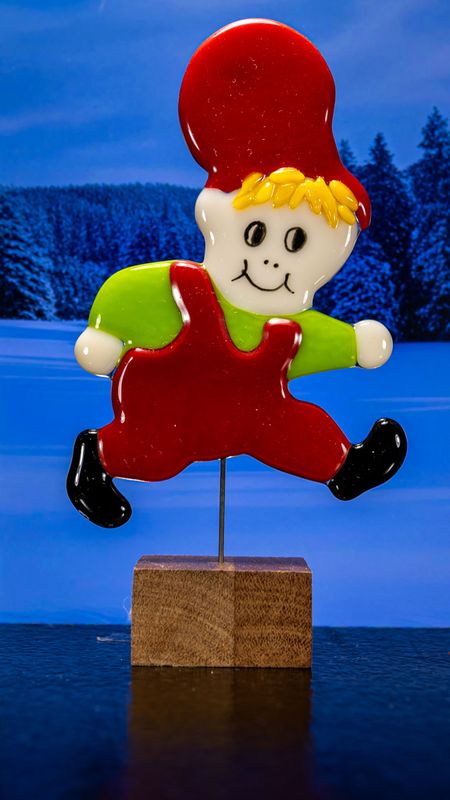 Glasfigur Nissedreng med grøn bluse, løber mod højre, på træfod