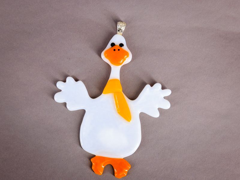 Hvid håndlavet glasgås med orange næb, fødder og gult tørklæde.
