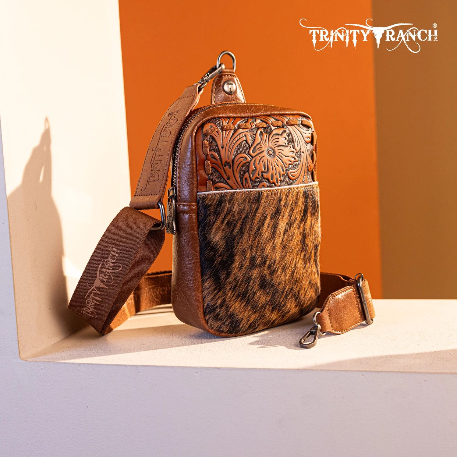 TRINITY RANCH HAIR-ON COWHIDE TOOLED SLING BAG
