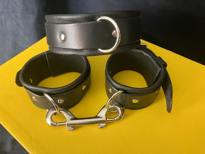 An image of the bondage cuffs and collar in black with silver hardware - and double clip addition for the cuff joining.