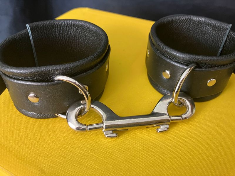 Close-up of black leather bondage cuffs with double-clip joining them