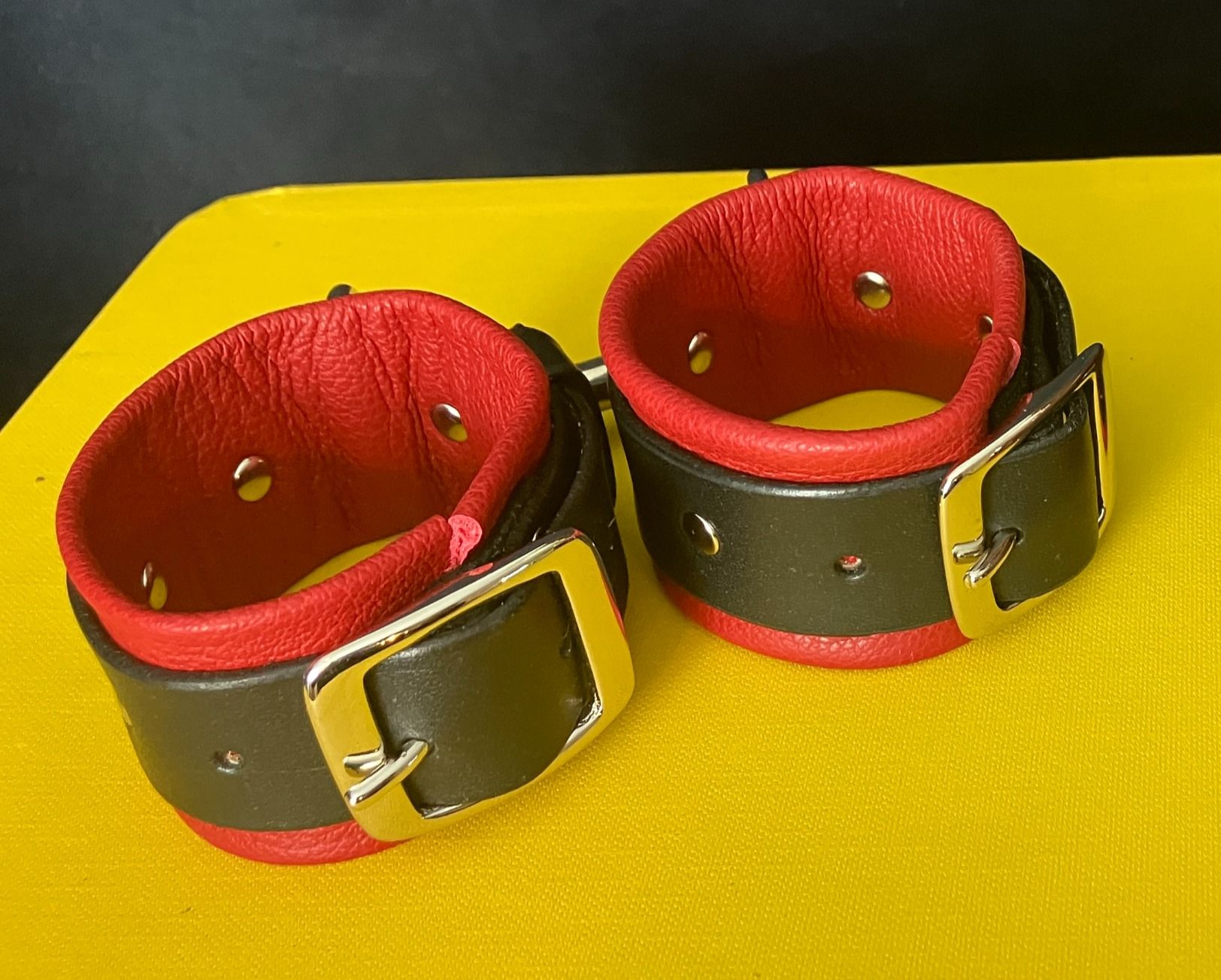 Close-up of black leather bondage cuffs with double-clip joining them