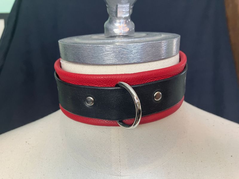 Leather bondage collar displayed on mannequin neck, in red/black