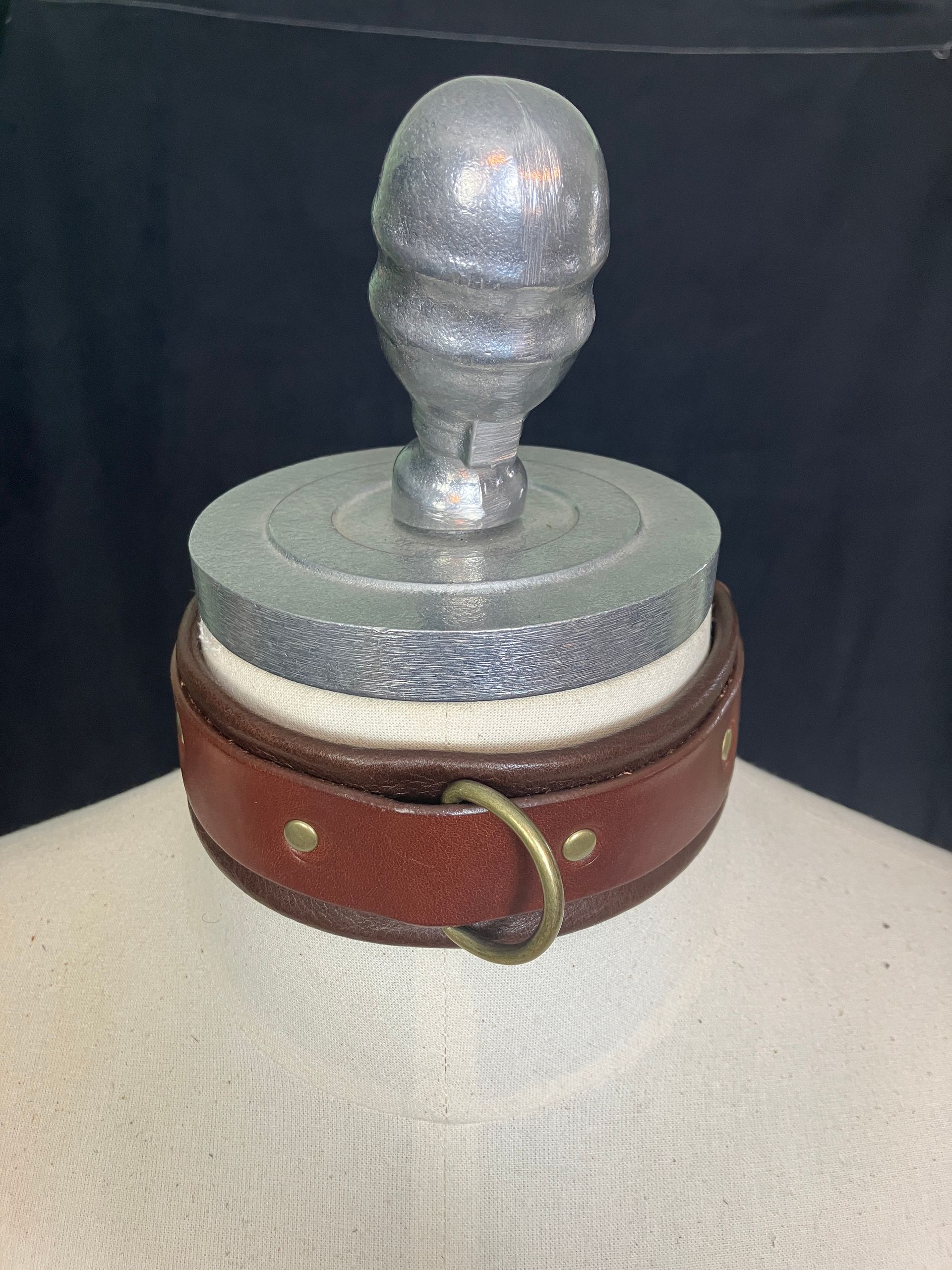 Leather bondage collar displayed on mannequin neck, in red/black