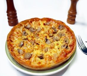 A delicious Pizza Messina topped with melted cheese, tender chicken pieces, and savory mushrooms on a golden, crispy crust. The pizza is garnished with a sprinkle of herbs, giving it a fresh and appetizing look. Served hot on a wooden board, ready to be enjoyed.