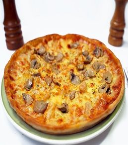 A delicious Pizza Messina topped with melted cheese, tender chicken pieces, and savory mushrooms on a golden, crispy crust. The pizza is garnished with a sprinkle of herbs, giving it a fresh and appetizing look. Served hot on a wooden board, ready to be enjoyed.