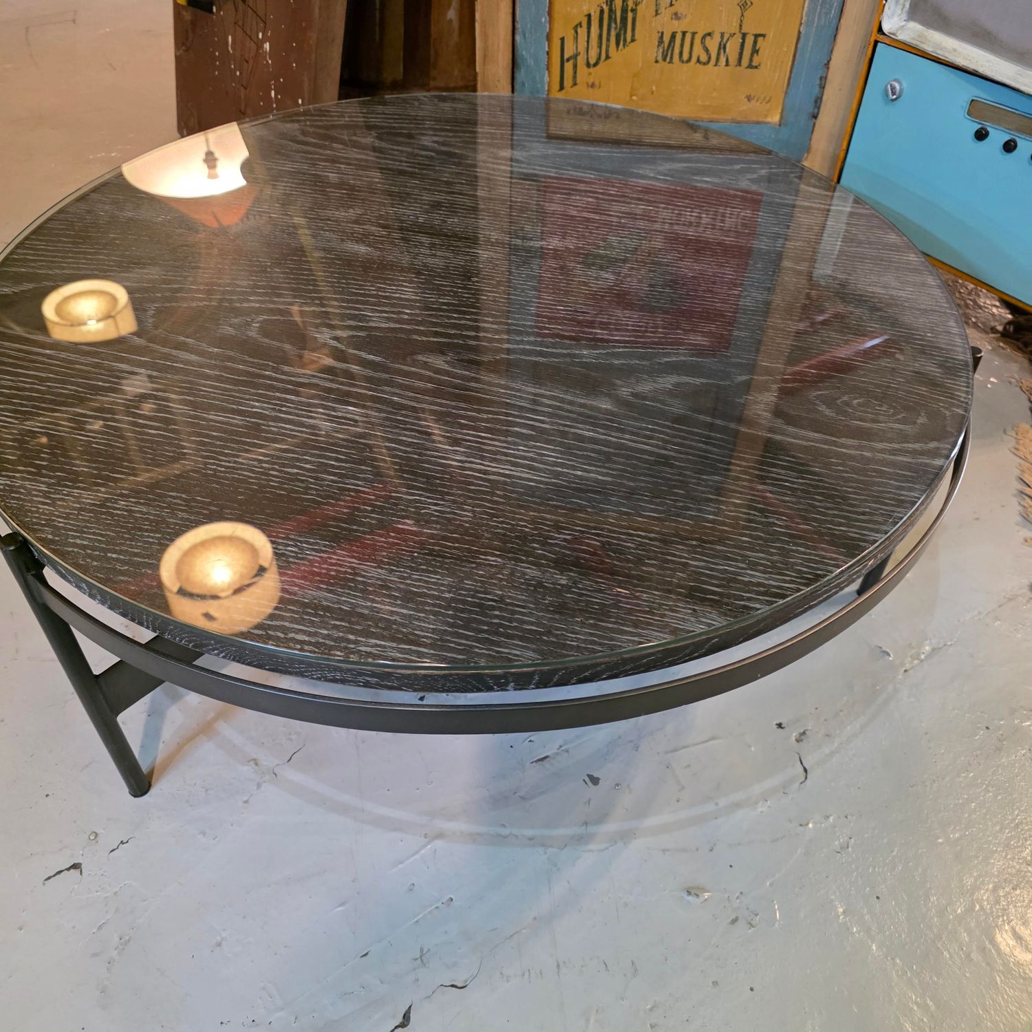 ROUND COFFEE TABLE WITH A GLASS TOP AND A BLACK METAL VASE