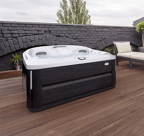 spa noir et blanc sur terrasse en bois avec mure gris en pierre 