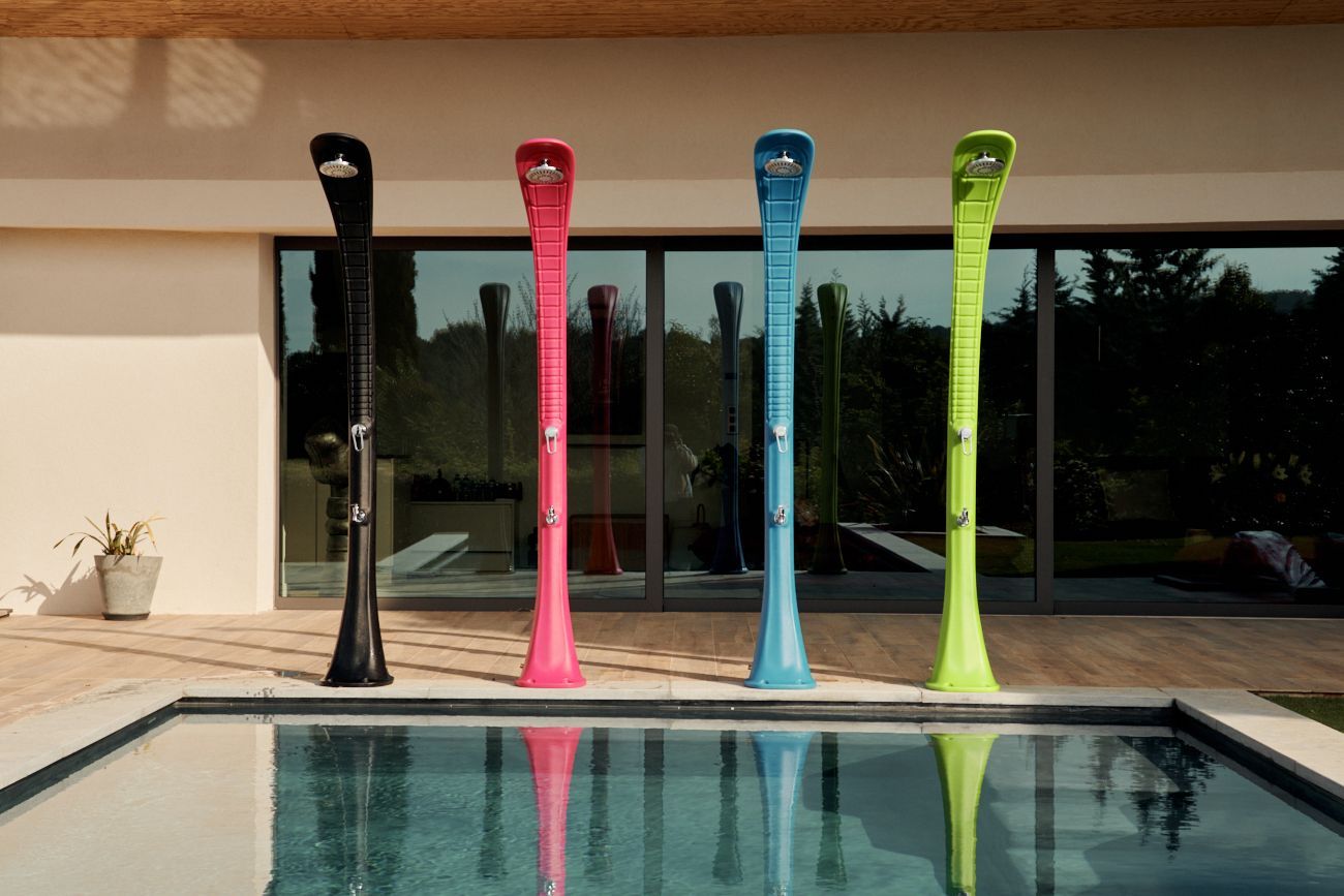 4 douche extérieur de 4 couleur  sur une terrasse au board d'une piscine