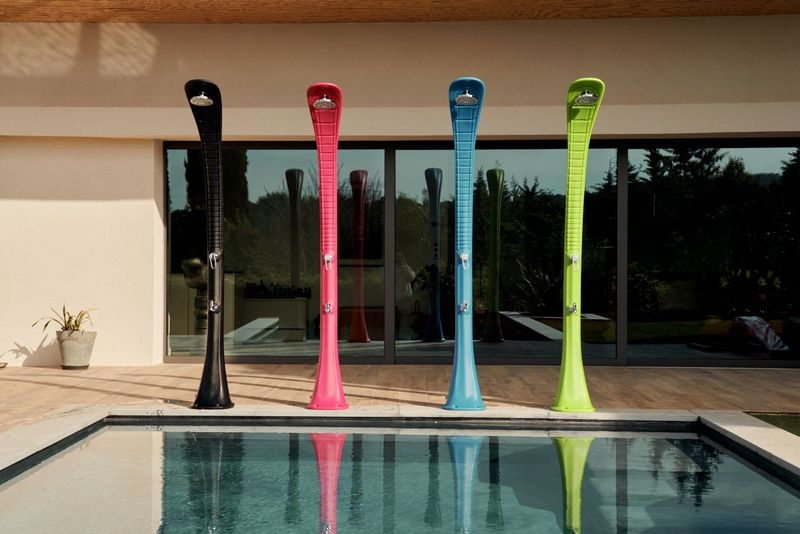 4 douche extérieur de 4 couleur  sur une terrasse au board d'une piscine