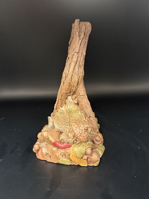 Sculpted Figure. USA. Tom Clark. Reston. Signed. Phone Holder or Bookstand: Gnome in Acorn Hat, Holding a Penny, Resting at Base of Tree Trunk. 1986. 6.5&#39;&#39;H