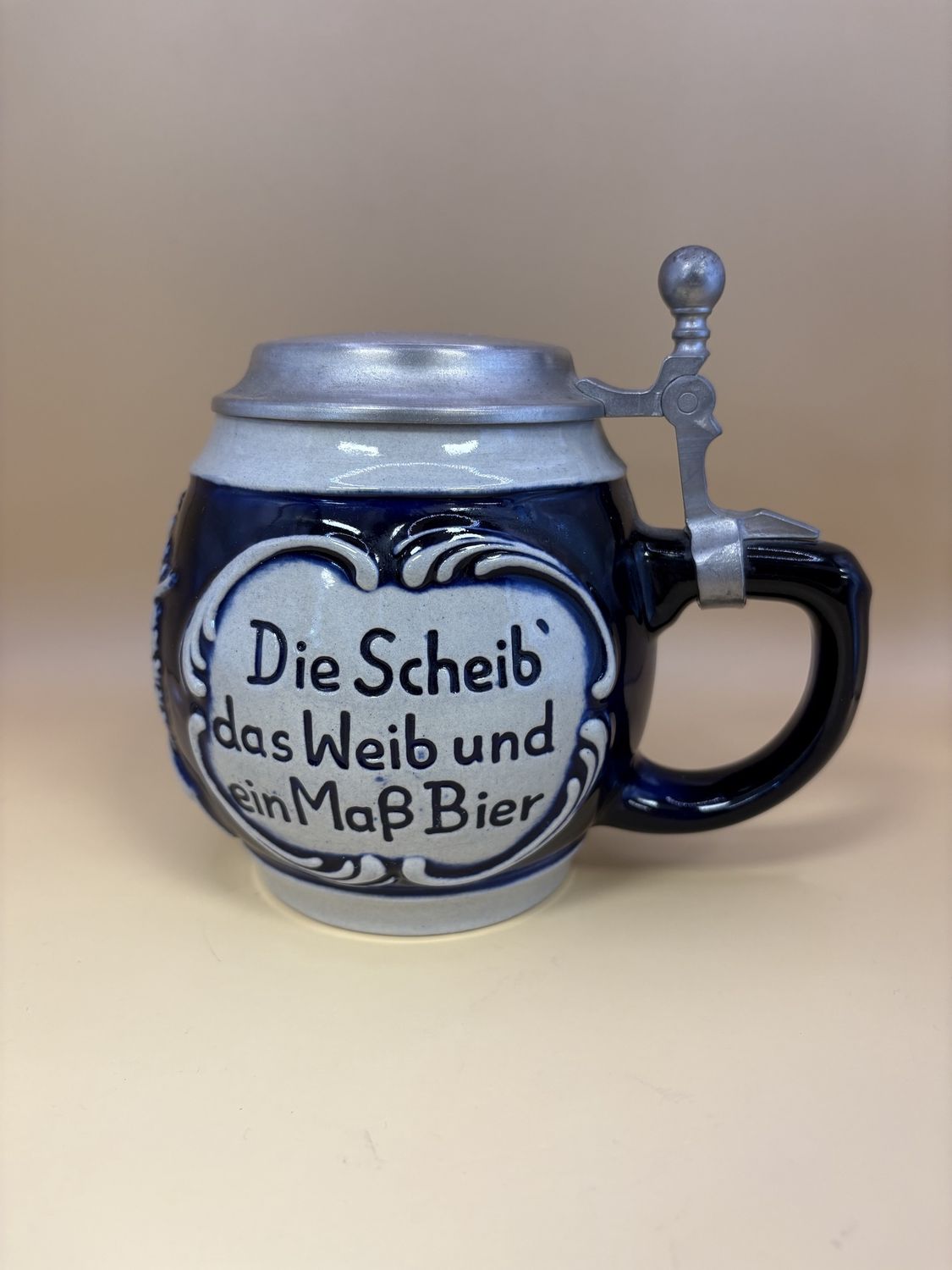 Stein. West Germany. Stein with Engraved Lid. Translation of sides: &quot;The target, the woman, and a pint of beer are the marksman&#39;s greatest pleasure&quot;. Blue &amp; Gray. 1992. 5.75&quot;H