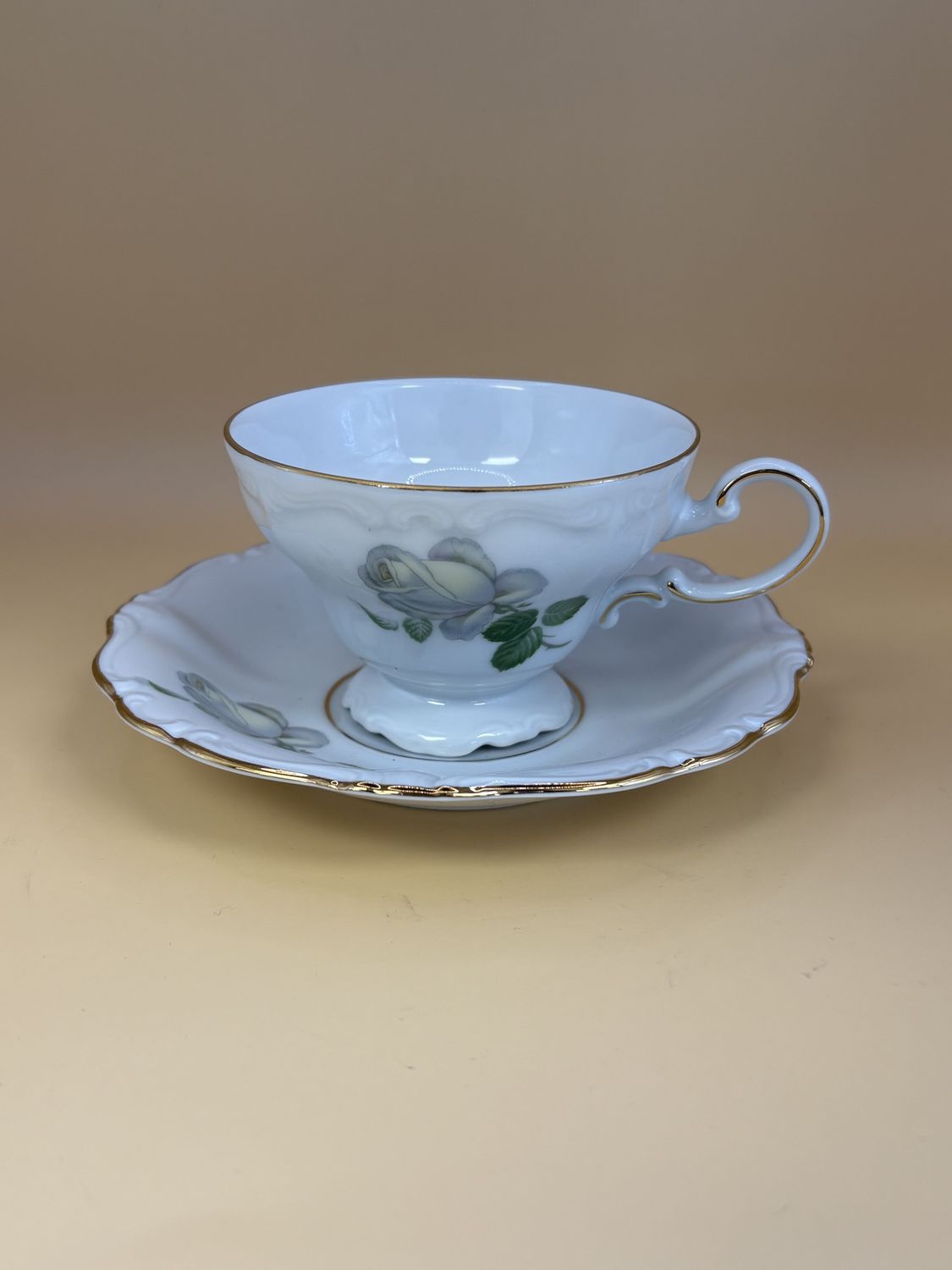 Porcelain. Germany. Johann Haviland Bavaria. Footed Tea Cup and Saucer.  White Rose Design with Green Leaves and Gold Trim. Collectible.  2pcs.