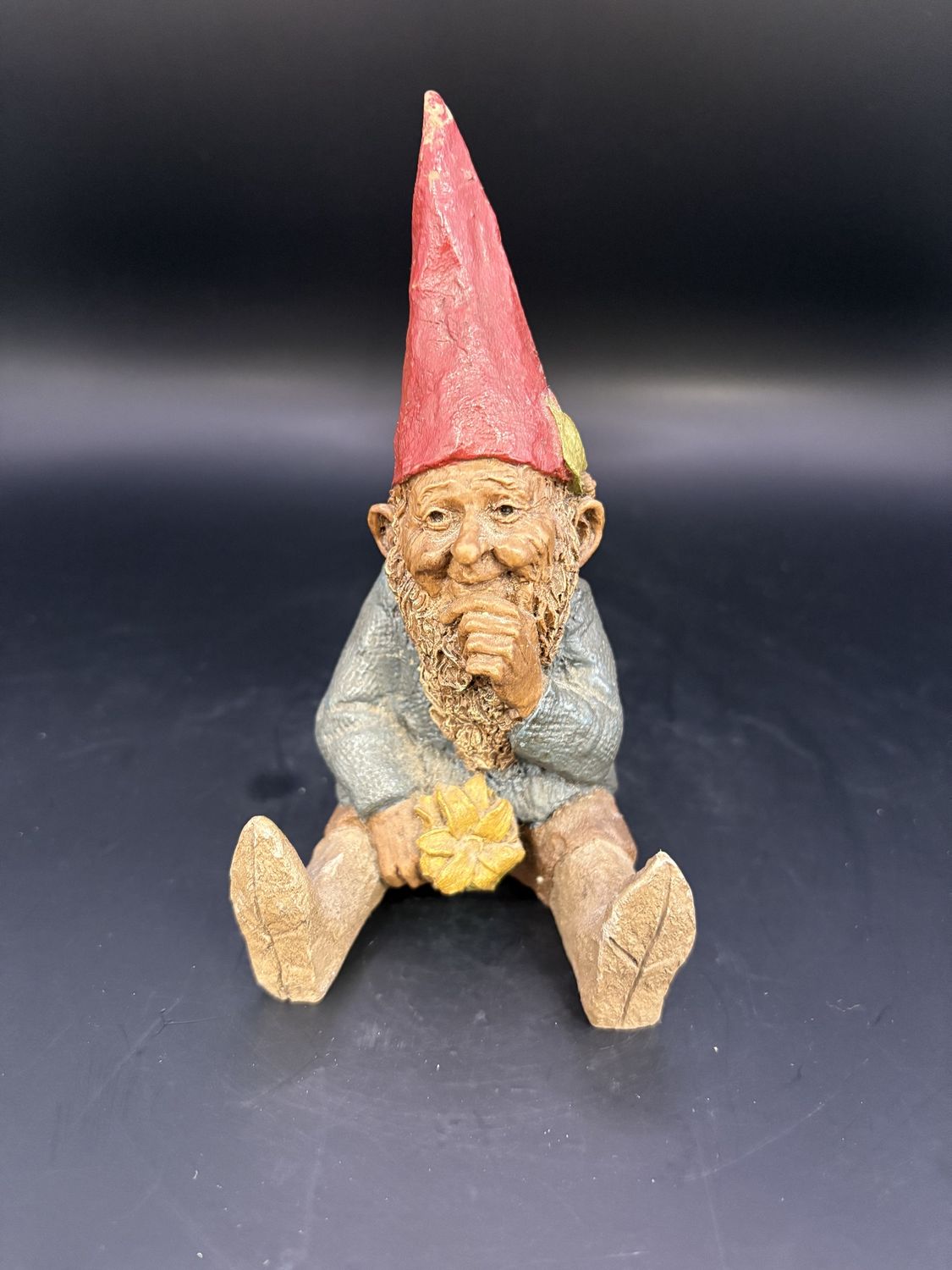 Sculpted Figure. USA. Tom Clark. Mugmon. Gnome Sitting w/Legs Out, Holding a Yellow Flower in One Hand &amp; Chin in Other. 1984. 5&quot;H