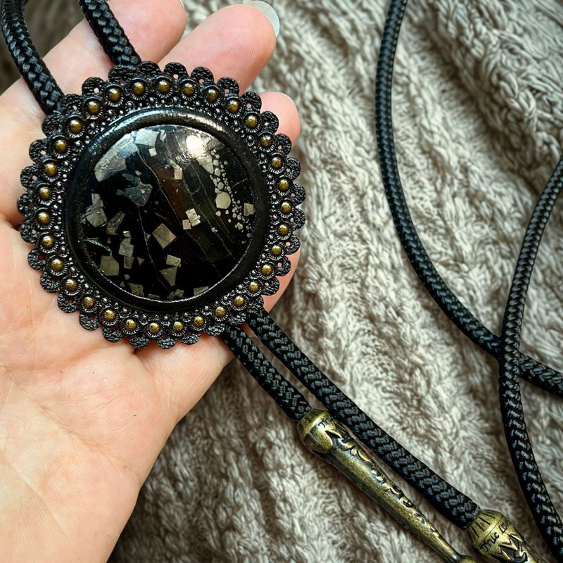Handmade bolo tie with pyrite in onyx, framed in tooled leather