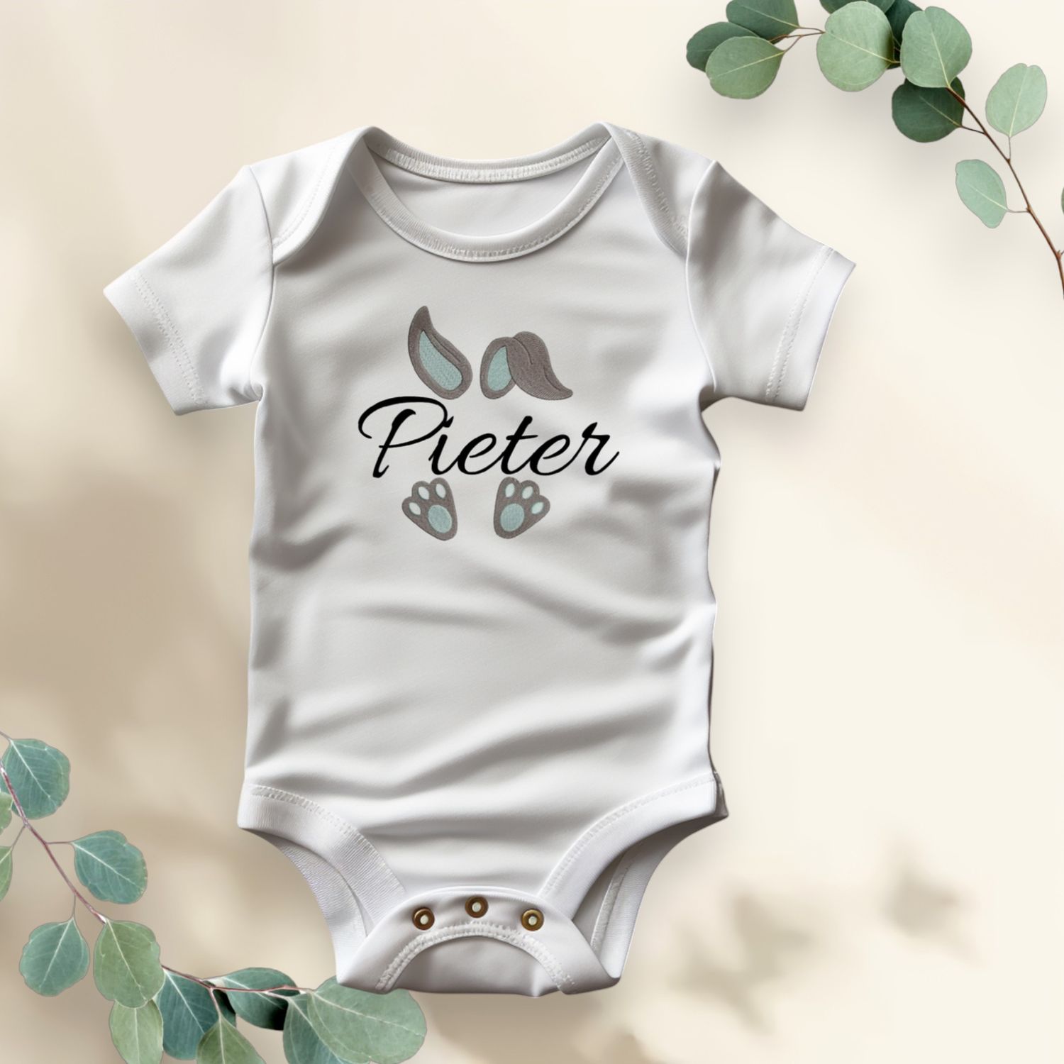 Wit rompertje met illustraties van oortjes, pootjes en de naam &quot;Feline&quot; in sierlijk lettertype.