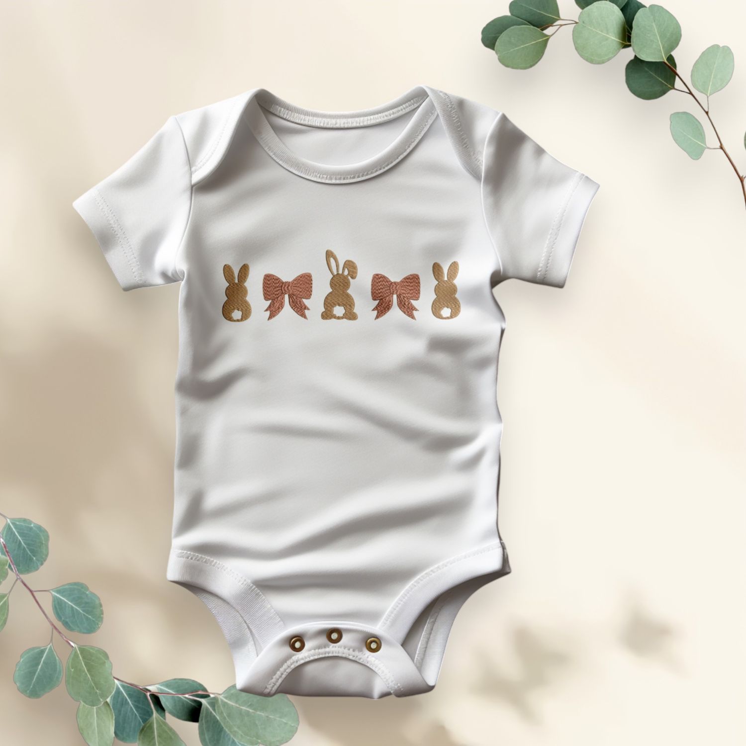 Witte babyromper met gouden konijntjes en strikken, ideaal als stijlvolle Paasoutfit of uniek kraamcadeau.