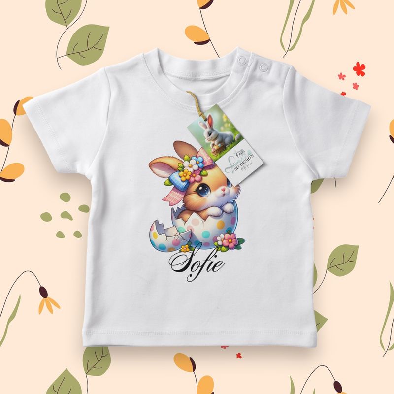 Wit baby T-shirt met een schattig konijntje, vrolijk in een kleurrijk ei met bloemen en stippen.
