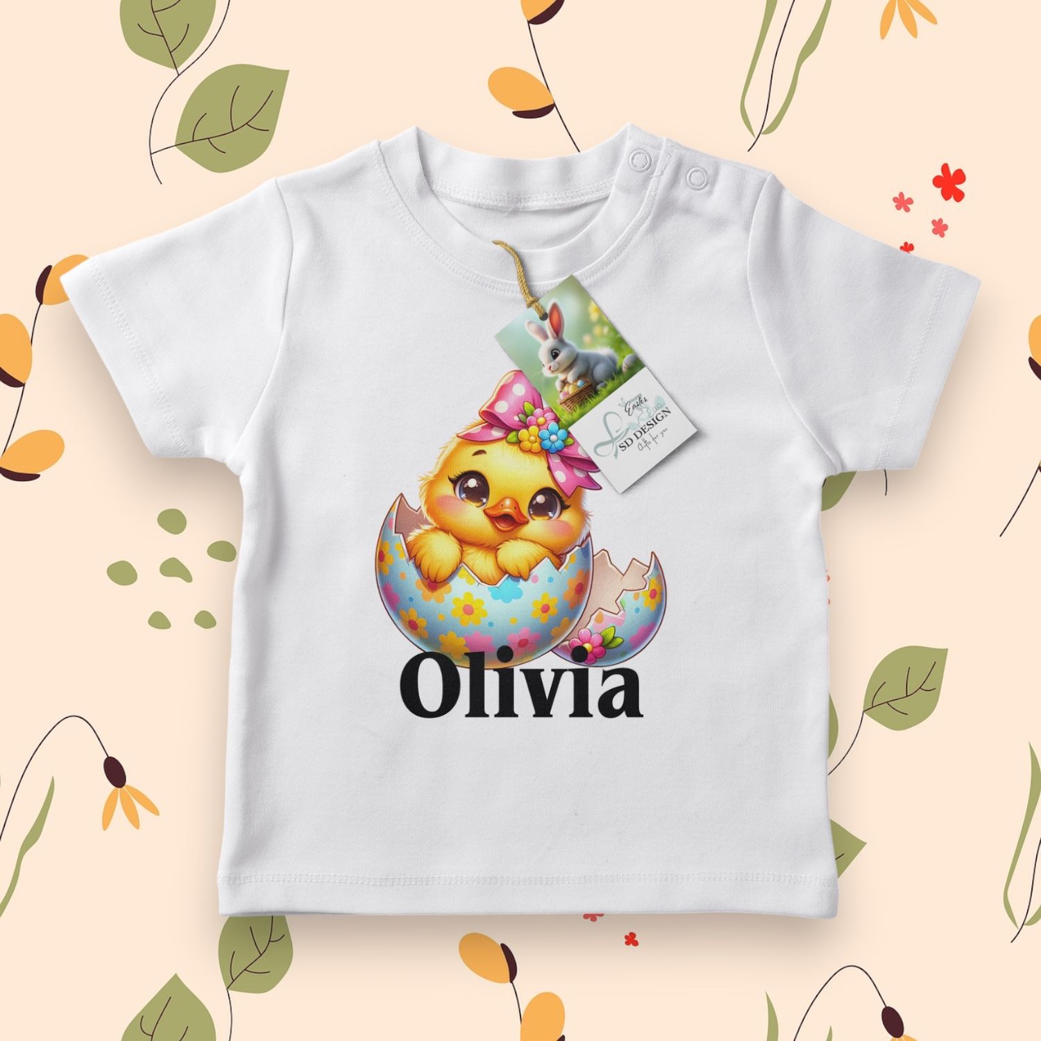 Wit baby T-shirt met een schattig geel kuikentje, versierd met een roze strik en een vrolijk paasei.