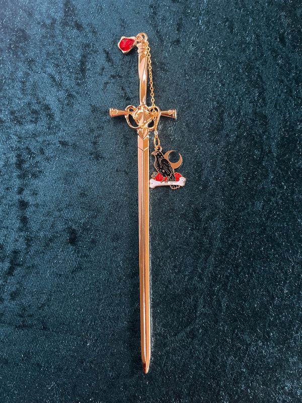 Lesezeichen "Schwert" in Gold-Optik,  mit rotem Stein, Kettchen und Anhänger "Rabe, Knochen & Halbmond"