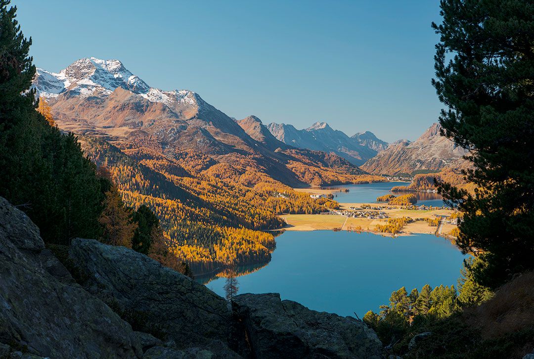 Blick von einem felsigen Hang auf den tiefblauen Silsersee und Silvaplanersee im Engadin