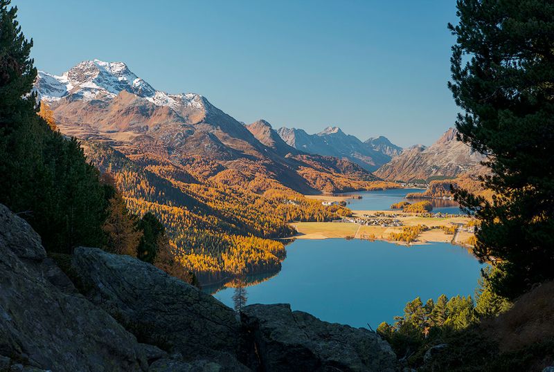 Blick von einem felsigen Hang auf den tiefblauen Silsersee und Silvaplanersee im Engadin