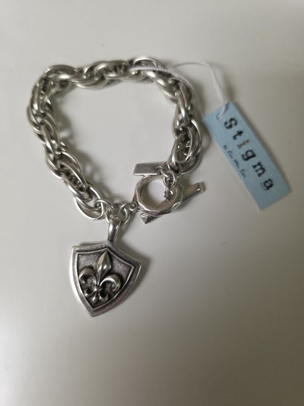 Stigma men's bracelet with a toggle clasp and a shield charm featuring a fleur-de-lis emblem