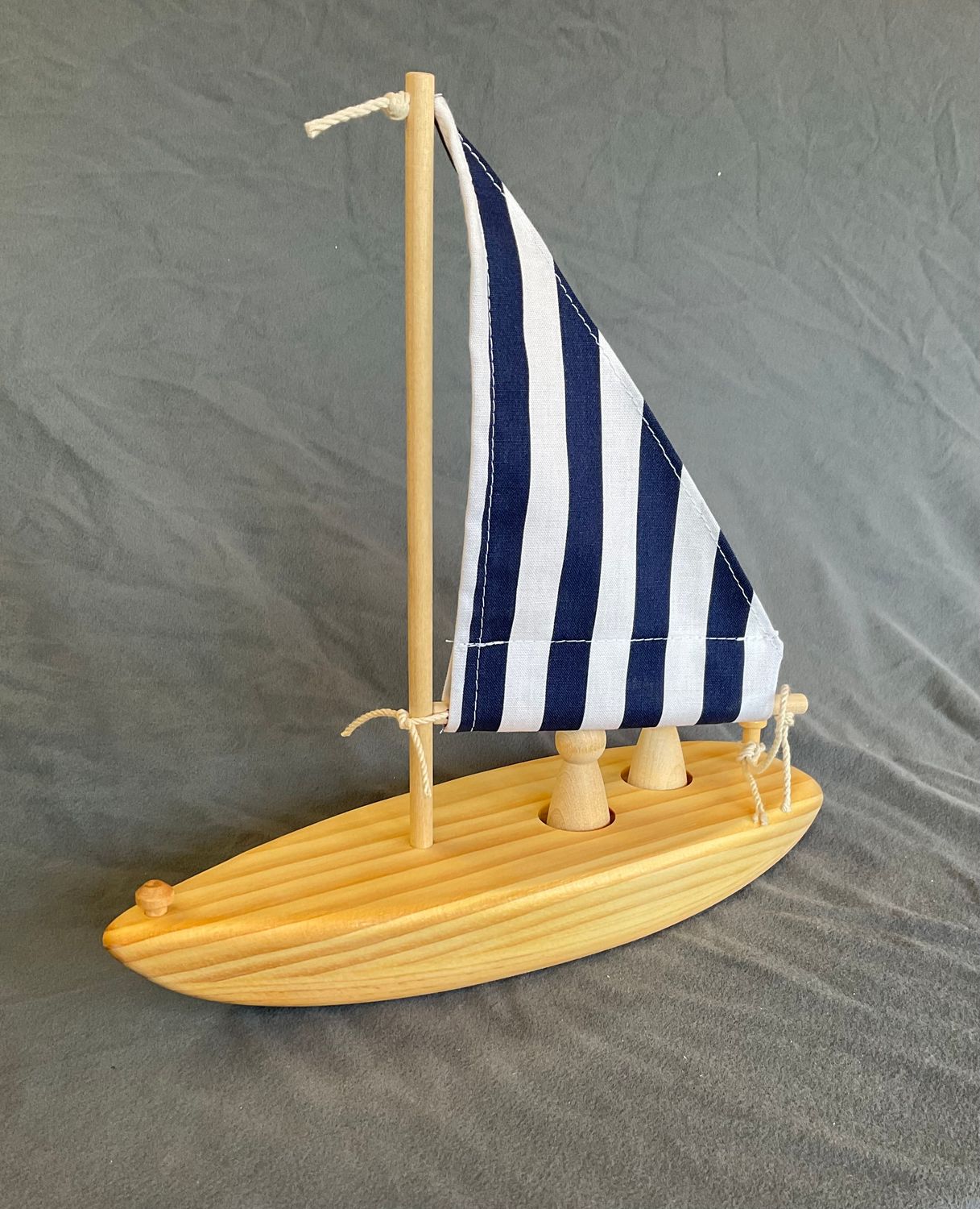 wooden toy sailboat, blue and white stripe sail