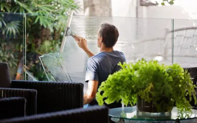 A man is cleaning a window with a squeegee in a living room.
