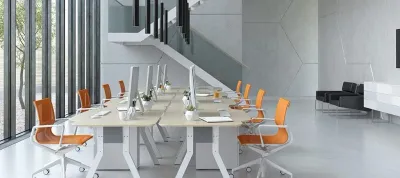A large office with a lot of desks and chairs and a staircase.