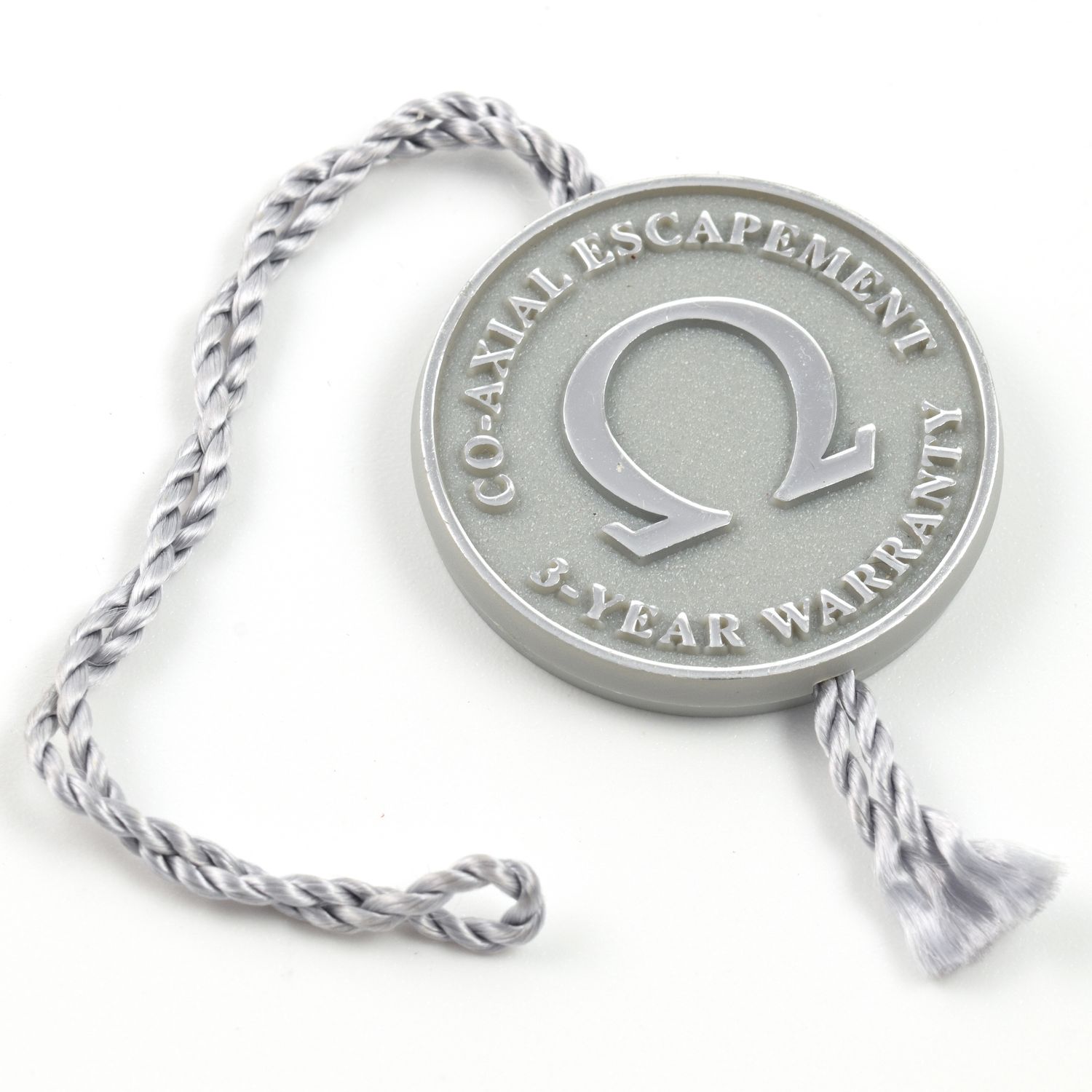 Omega Co-Axial Escapement 3-Year Warranty watch swing hang tag with silver string