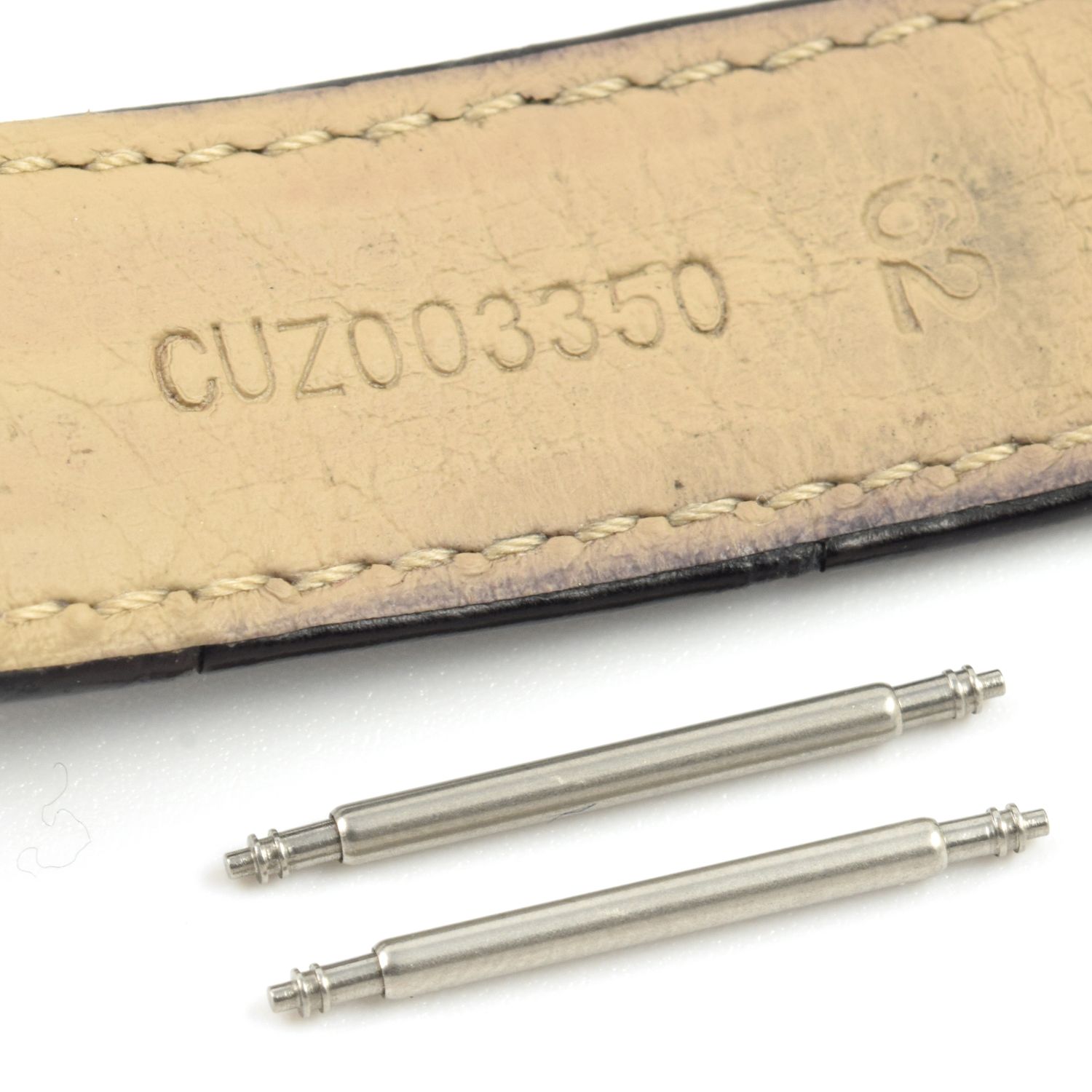 Two stainless steel spring bars placed next to the underside of an Omega Globemaster watch strap stamped CUZ003350, shown on a white background.