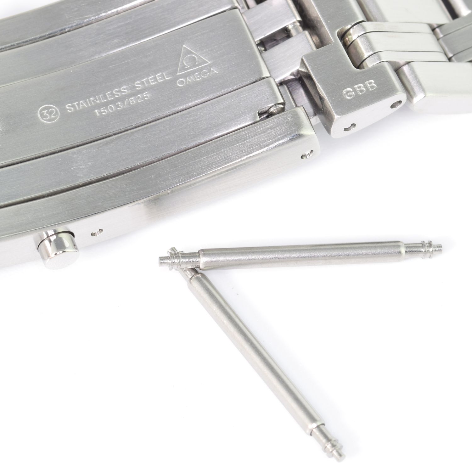 Two stainless steel watch spring bars placed next to an Omega Seamaster full size bracelet with 1503/825 engraved on the clasp, showing intended use for bracelet attachment.