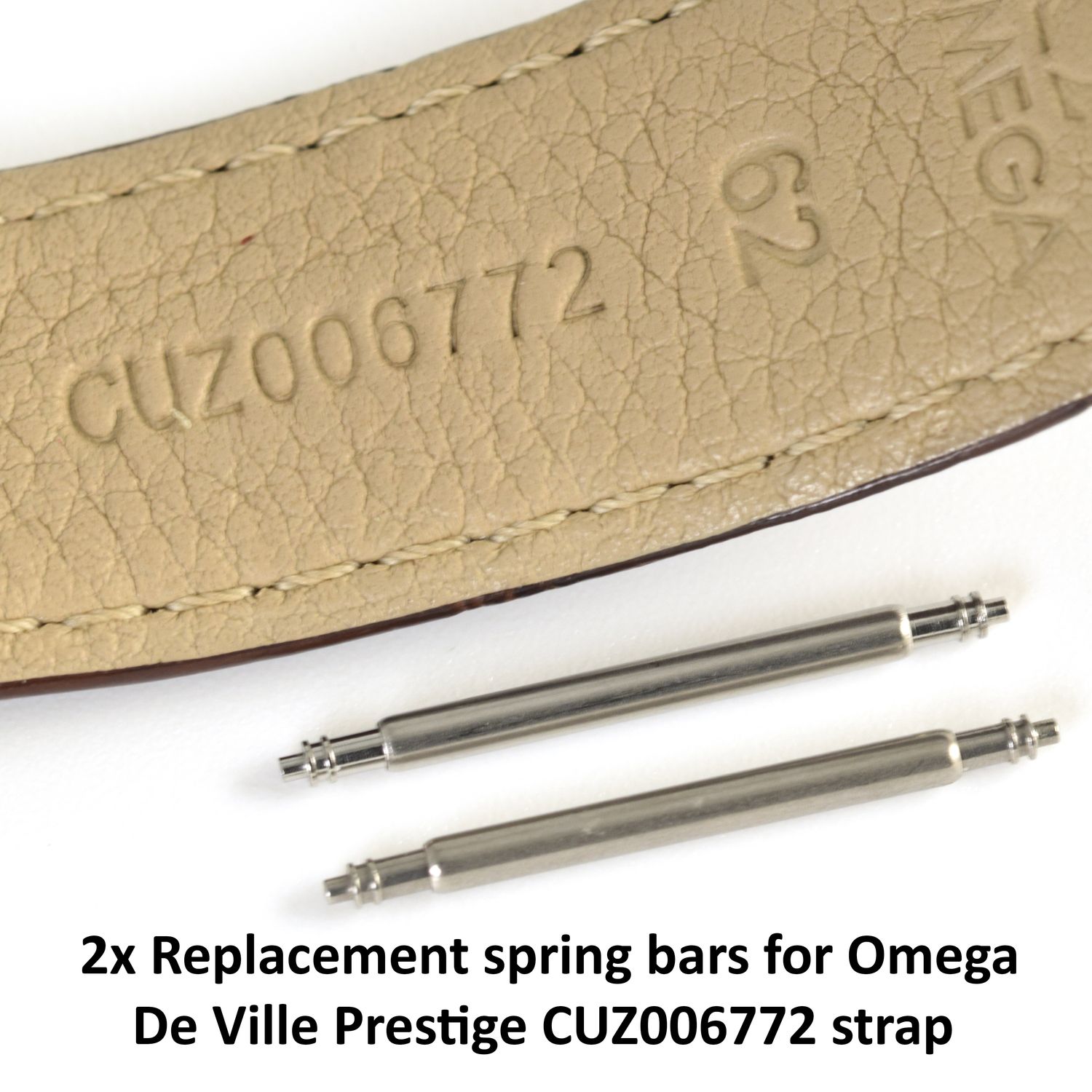 Two stainless steel watch spring bars placed beneath a tan Omega De Ville Prestige strap stamped CUZ006772, shown on a white background