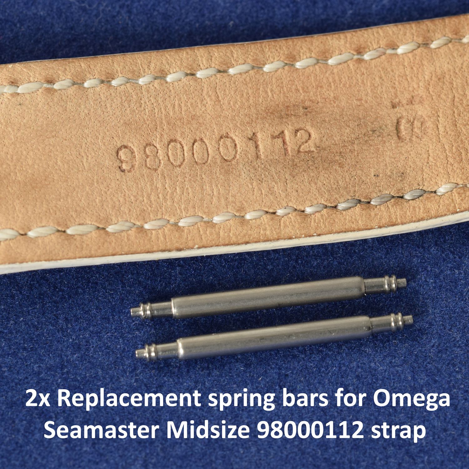 Two stainless steel spring bars positioned below a tan leather Omega Seamaster strap stamped 98000112, placed on a blue background with overlaid text reading “2x Replacement spring bars for Omega Seamaster Midsize 98000112 strap