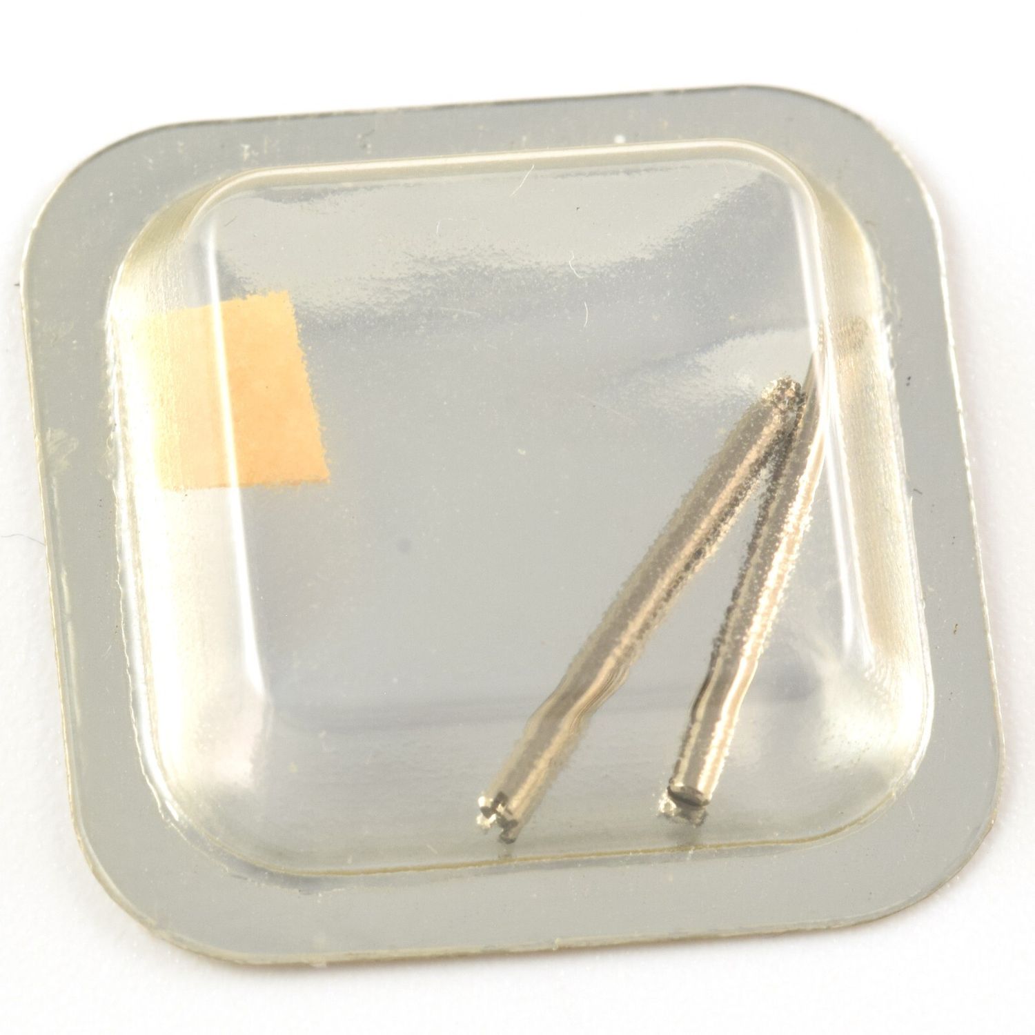 Two Cartier Must VLC watch clasp screws sealed in a clear blister pack on a silver square card with screws arranged diagonally