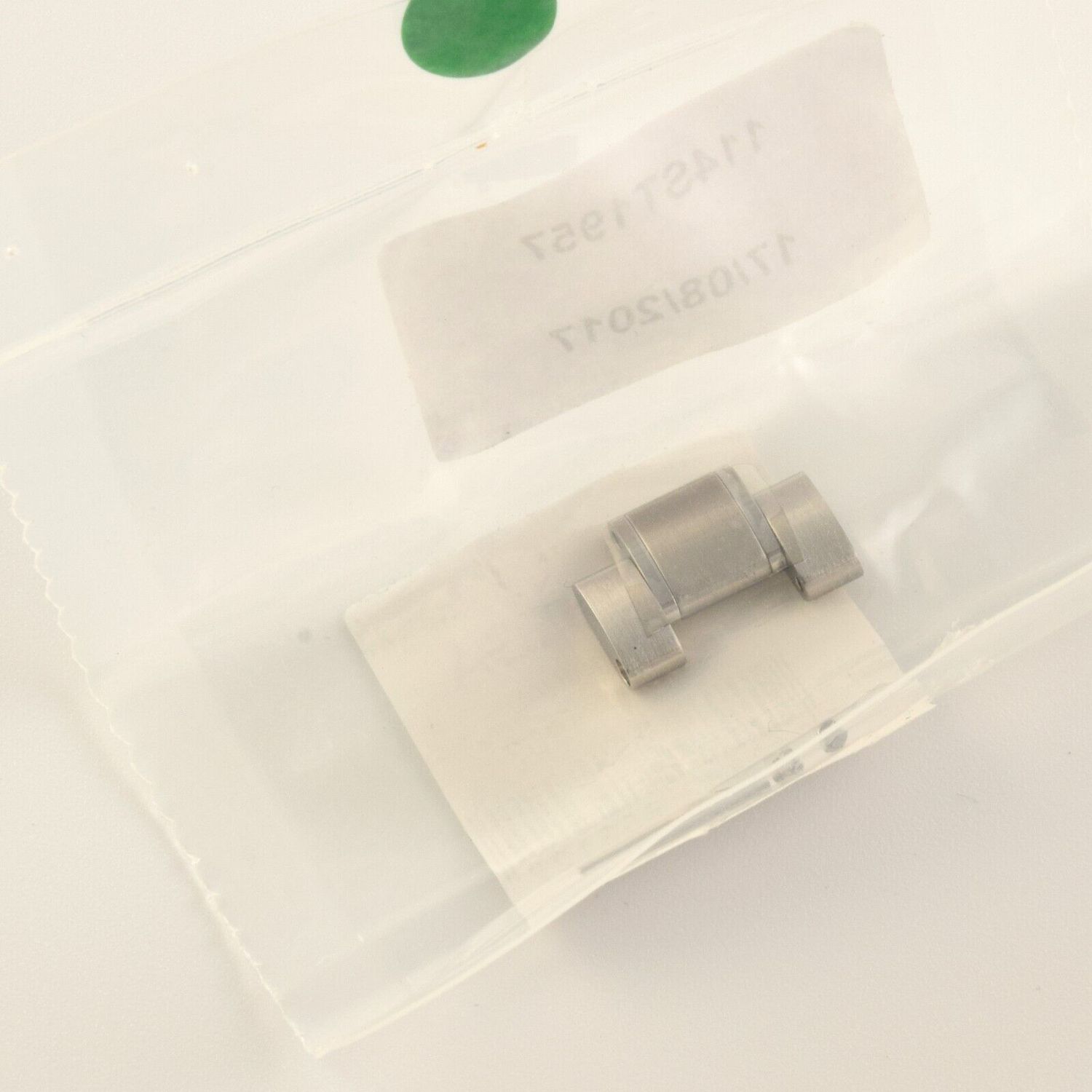 sealed plastic pouch containing a new Omega Speedmaster stainless steel 18mm wide bracelet link with brushed finish and opened screw packet