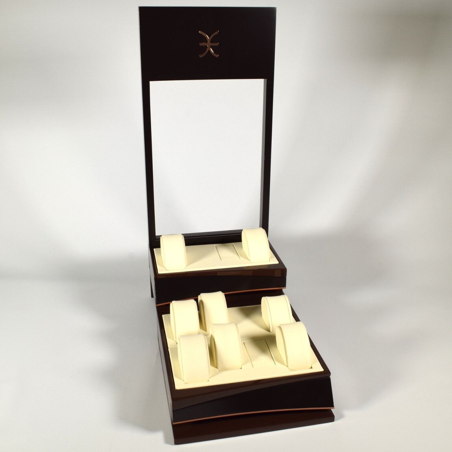 Authentic EBEL brown watch display stand with cream leather interior, 7 round cream leather watch pillows, and 2 EBEL-branded leather plugs shown on two-tiered base with tall backboard