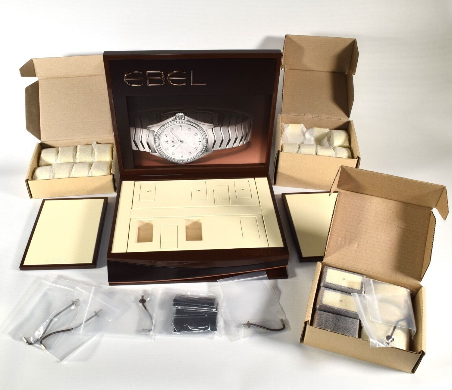 New authentic EBEL brown and cream leather watch display stand with large EBEL logo, unused components in original packaging, display trays, straps and boxed cushions included