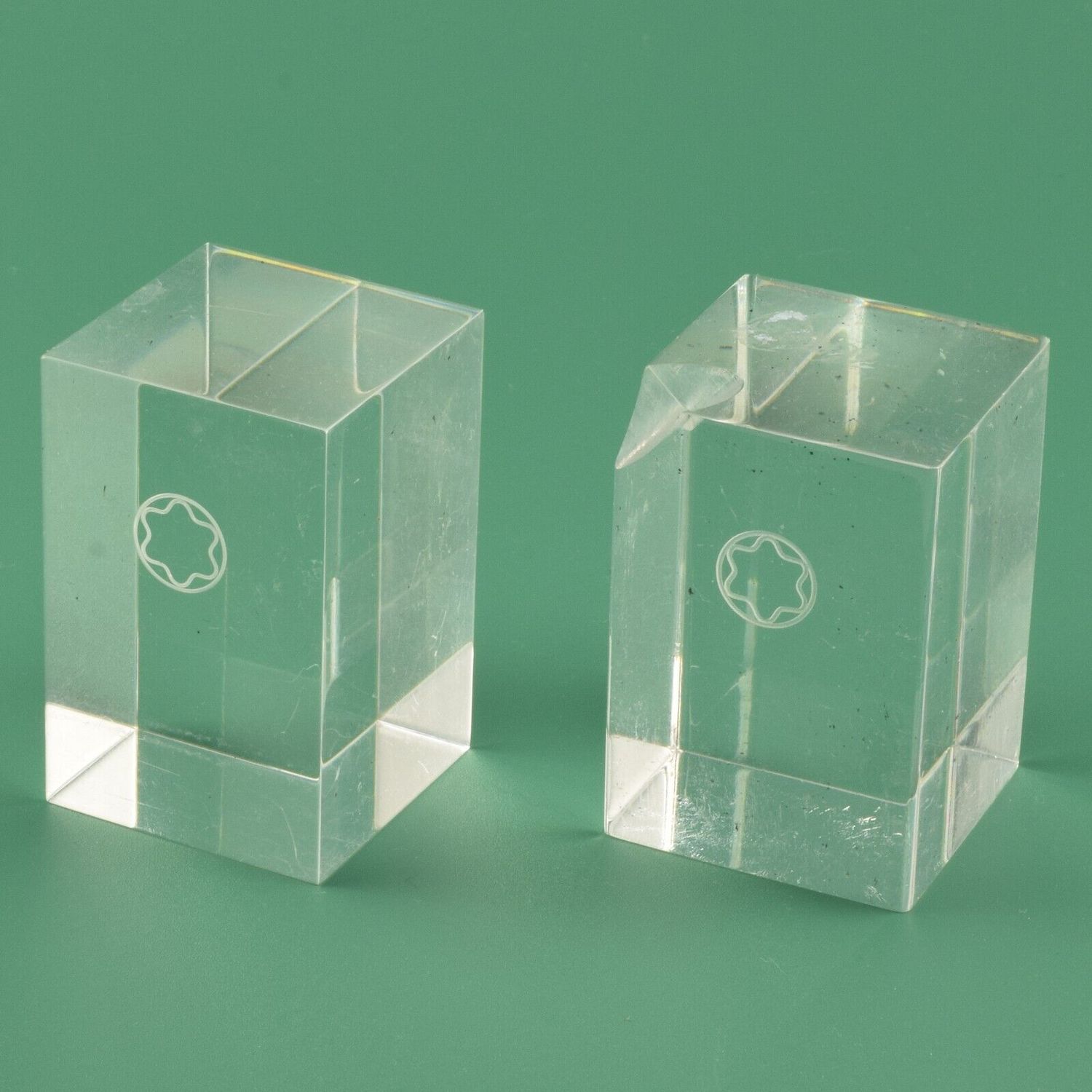 Two official Mont Blanc acrylic display cubes with Mont Blanc star logo, one with a pen notch and one without, both measuring 4x4x6cm and showing surface scratches