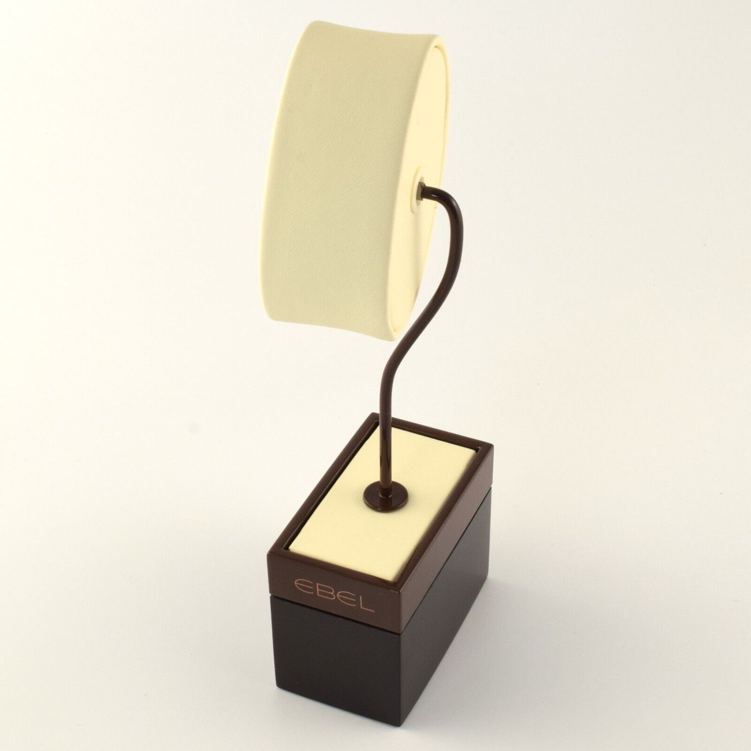 New authentic EBEL tall watch display stand with brown base and curved metal arm supporting a cream leather oval watch pillow, with EBEL logo printed on front of the base