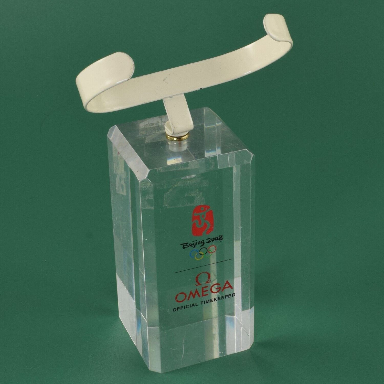 Omega Beijing 2008 horizontal acrylic watch stand with cream metal clip and Olympic branding on green background
