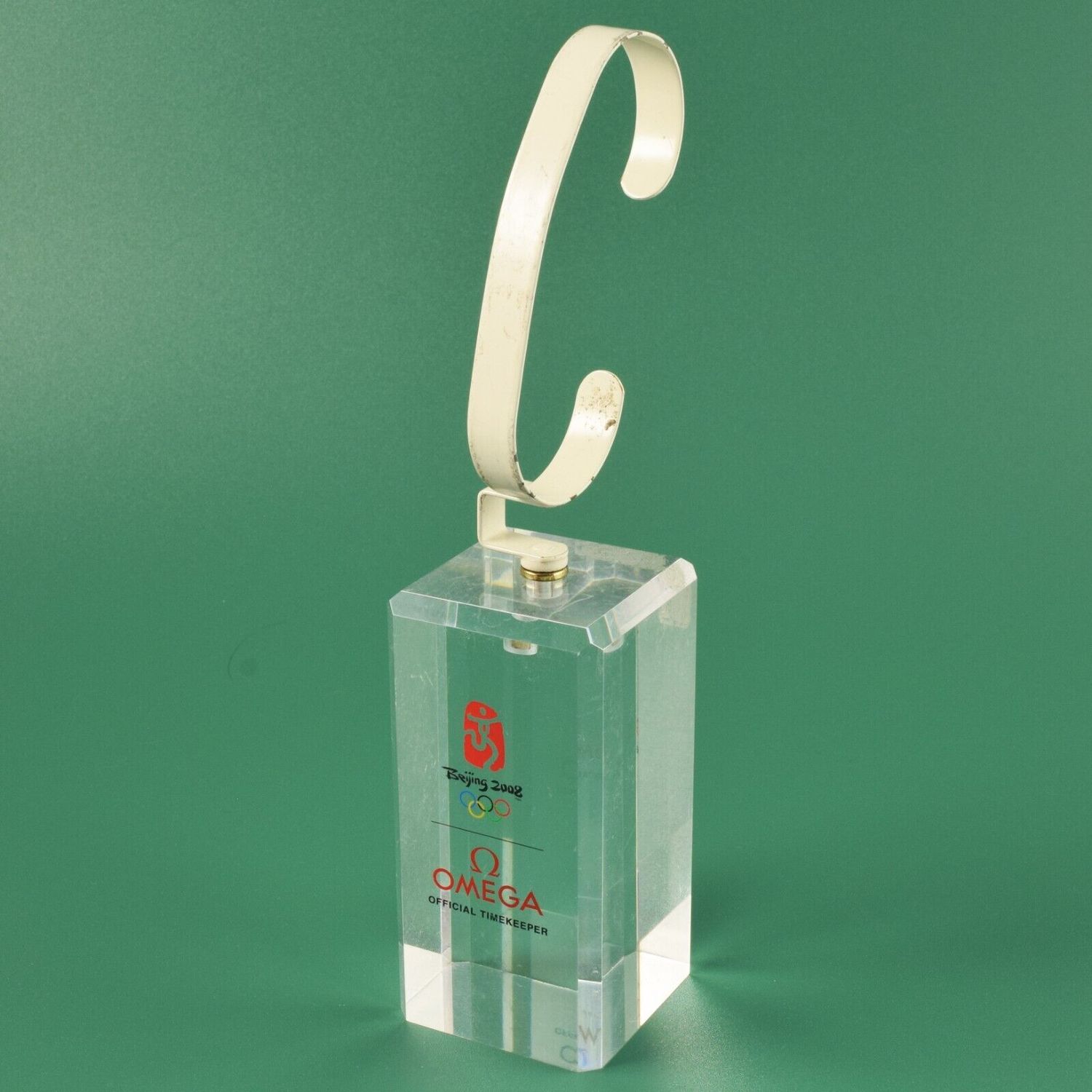 Omega Beijing 2008 Olympics acrylic watch stand with cream metal clip and red Omega logo on green background