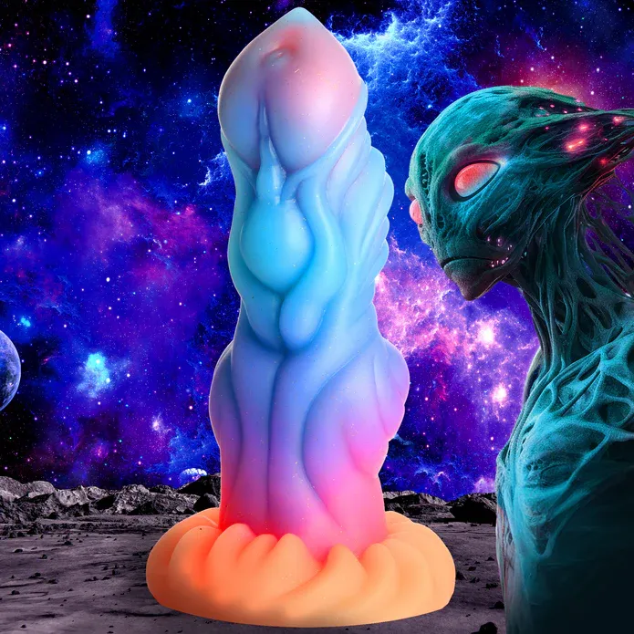The same of an image of silicone dildo modeled to look like an alien penis. Its pour features a pale pink core most visible at the tip, ranging from sky blue just below the head to hot pink nearer the base, finally ending in a bright orange base. It features a tapered tip, a prominent texture of smooth ridges and whorls, a slight knot towards the base, and a textured base to grind on. This image also features a background modeled to look like an otherworldly ground and sky, featuring a blue alien humanoid with blue, hairless features, red eyes, and a solemn expression. 