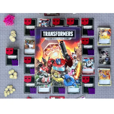 Transformers Deck-Building Game contents with box, Matrix cards, tokens, Energon cubes, and play area.