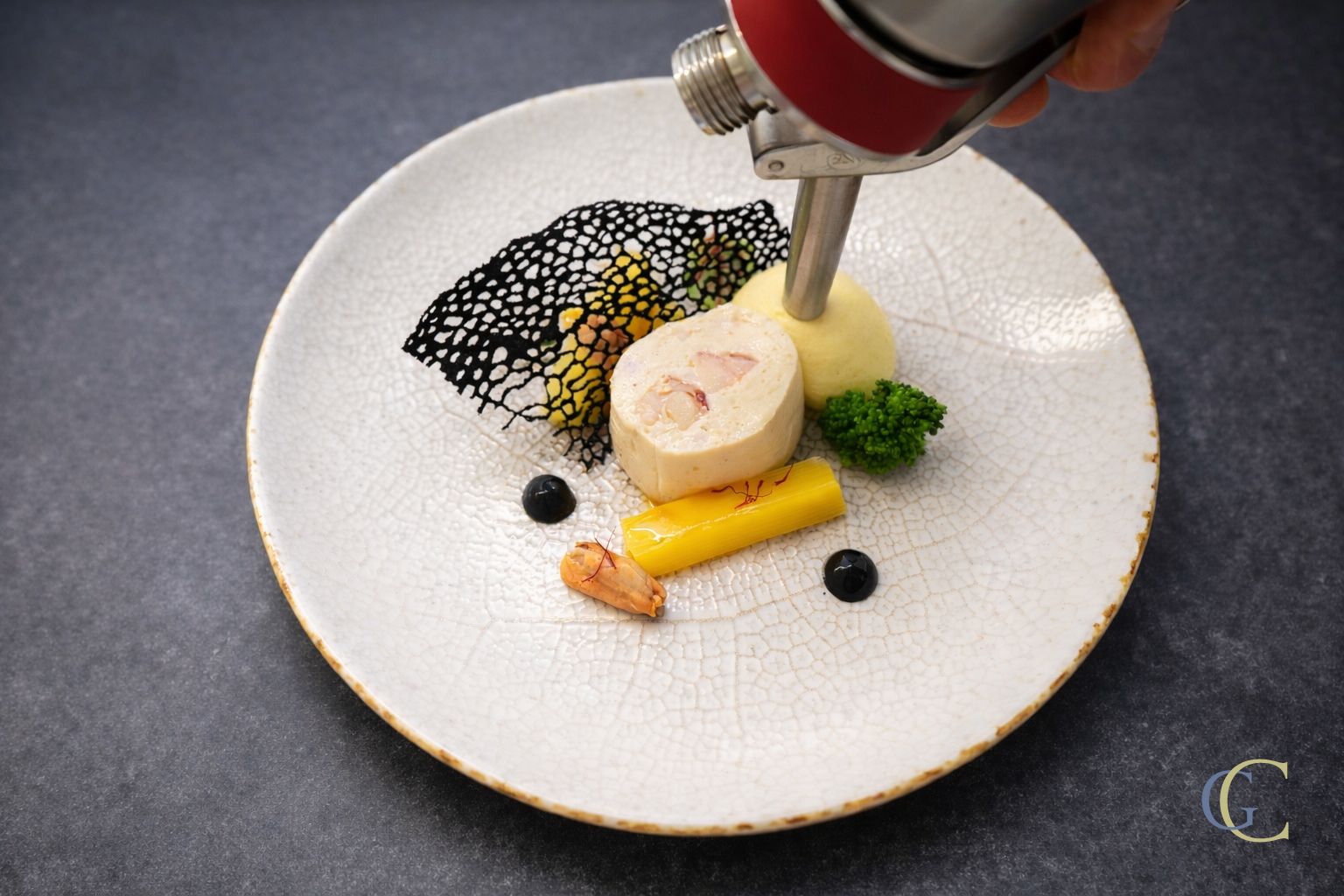 Cervelas de homard, moules et poireau, espuma au safran, tuile perlée à l'encre de seiche