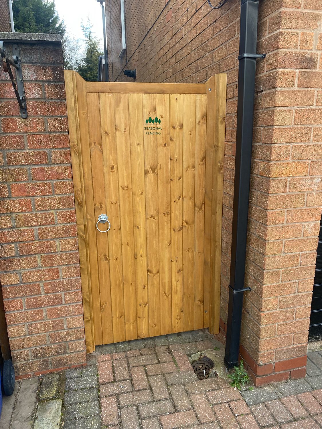 Natural finish tongue and groove timber side gate installed between brick walls.