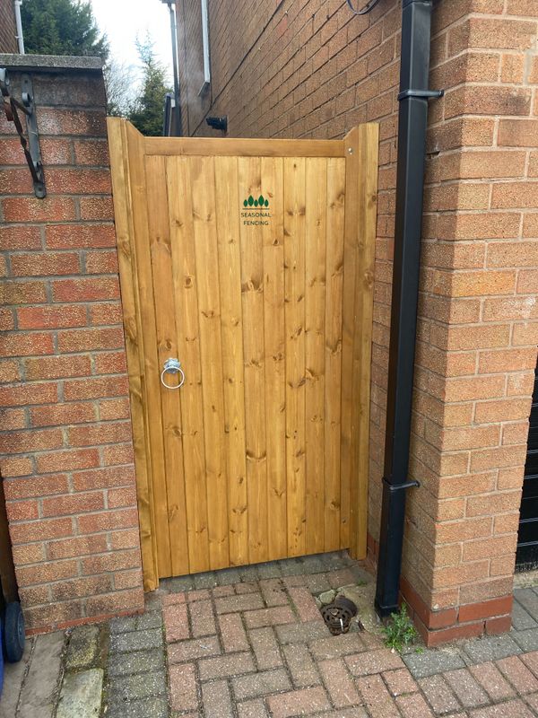 Natural finish tongue and groove timber side gate installed between brick walls.