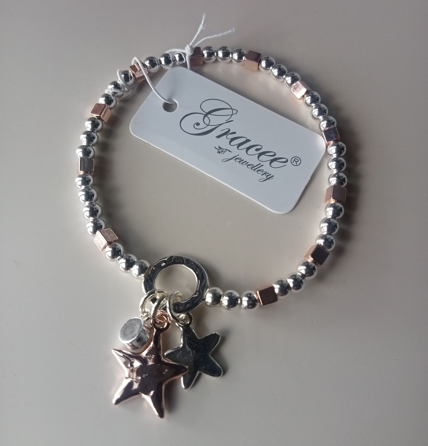 Elasticated silver and gold tone bracelet with two stars one star is gold tone and one charm with a stone